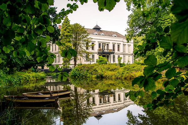 Rear view of Castle De Berckt in Baarlo with small boats on the water