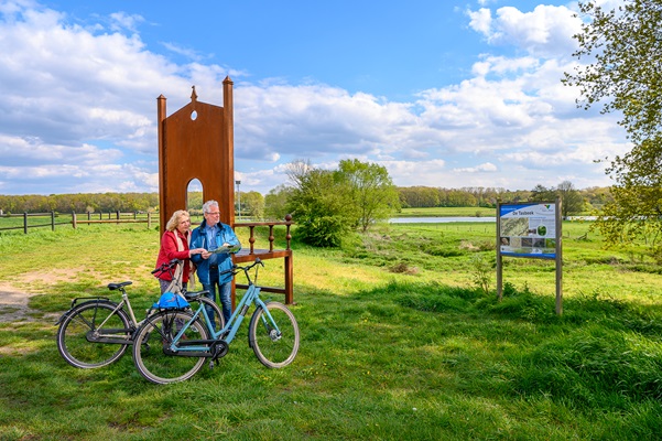 Frau und Mann betrachten die Landkarte auf dem großen Kunstwerk an der Maas in Kessel