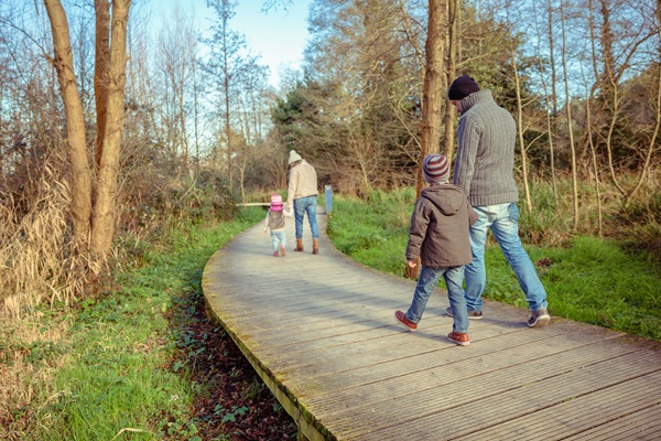 Family walks across a bat bridge in Hart van Limburg during winter