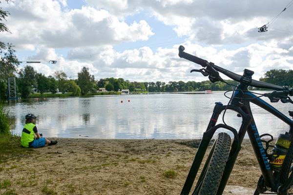 Mountainbike staat op de voorgrond terwijl de bestuurder aan het water geniet