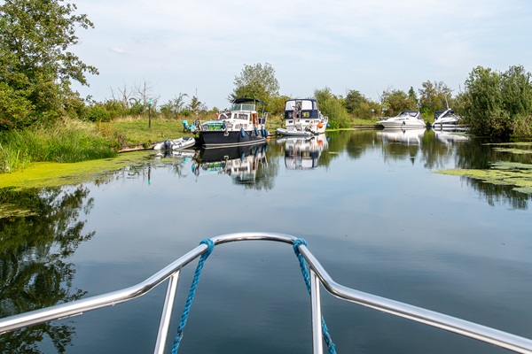 Luxe boten aangemeerd op de Maasplassen gezien van de boeg van een varende boot