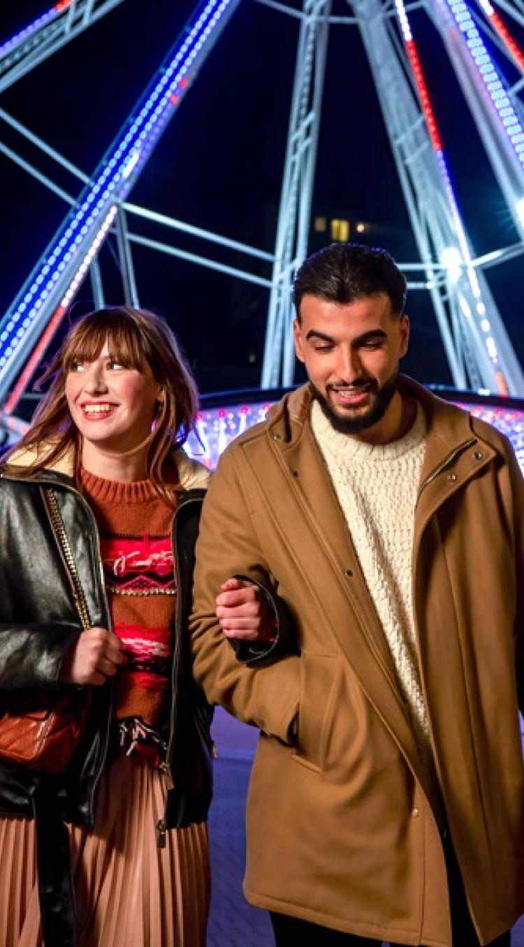 Twee mensen maken een selfie in een grote kerstkrans met rode ballen in Designer Outlet Roermond.