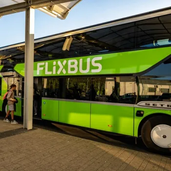 Reizigers stappen in bij een groene FlixBus op een bushalte onder een overkapping