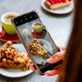 Vrouw maakt een foto van een stuk Limburgse vlaai met koffie, onderdeel van een bourgondisch arrangement van Hart van Limburg.